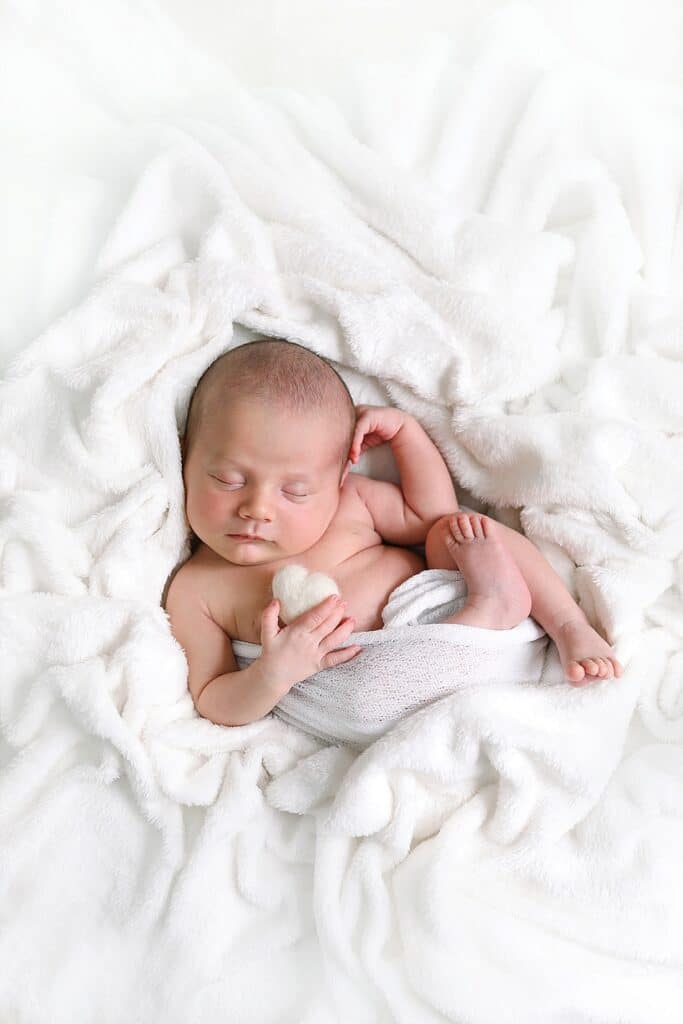 bébé endormi avec coeur blanc dans sa main